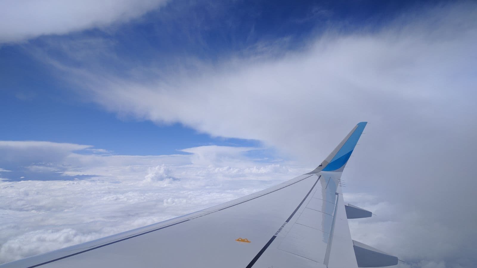 Aile d'avion au-dessus des nuages dans un ciel bleu