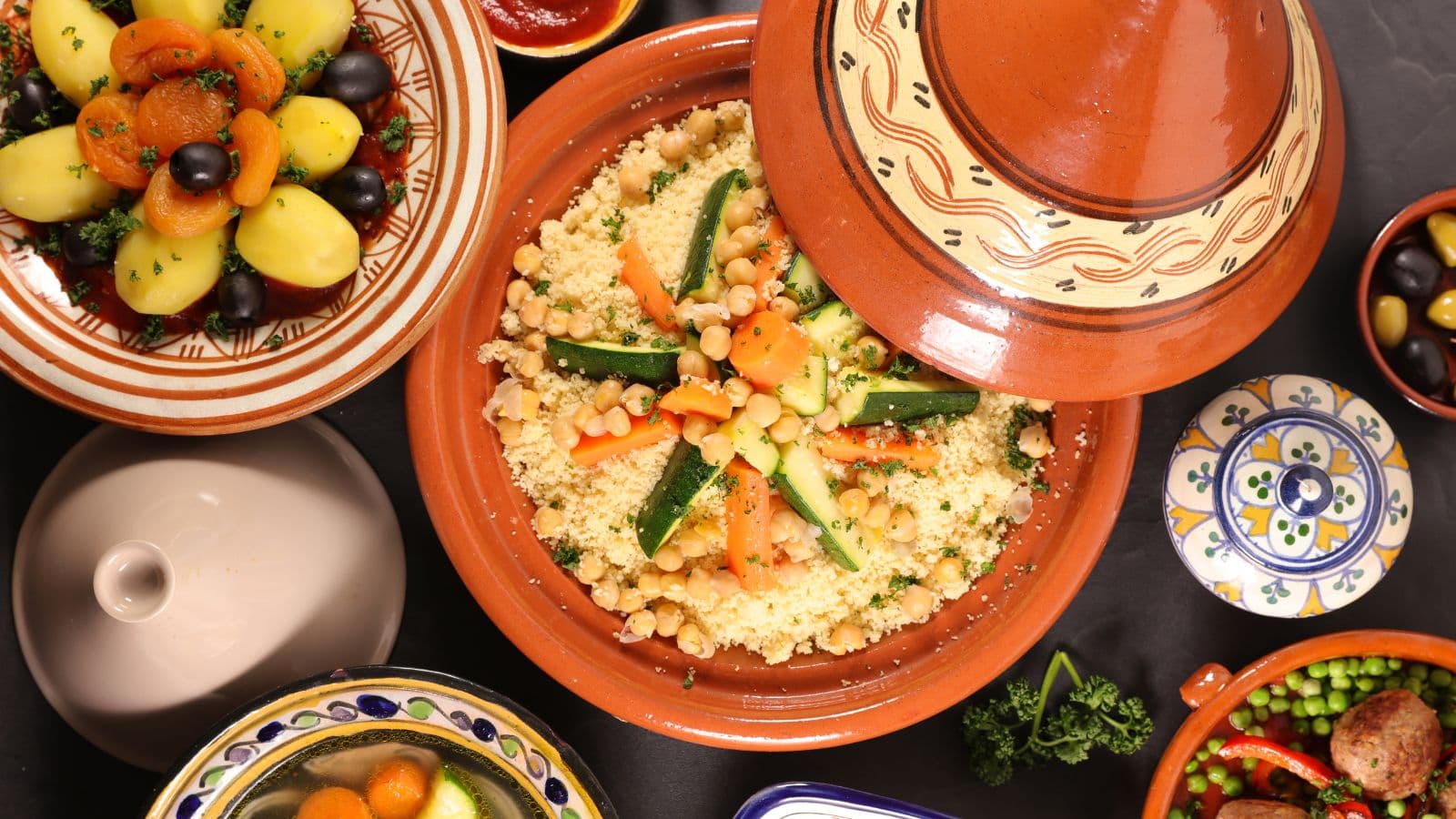 Couscous aux légumes entouré de plats en terre cuite