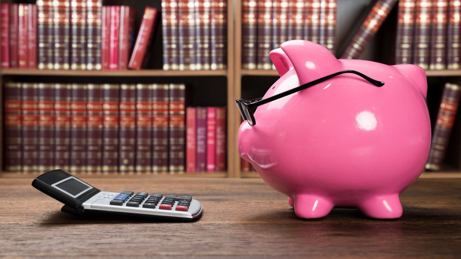 Tirelire rose, livres et calculatrice sur un bureau