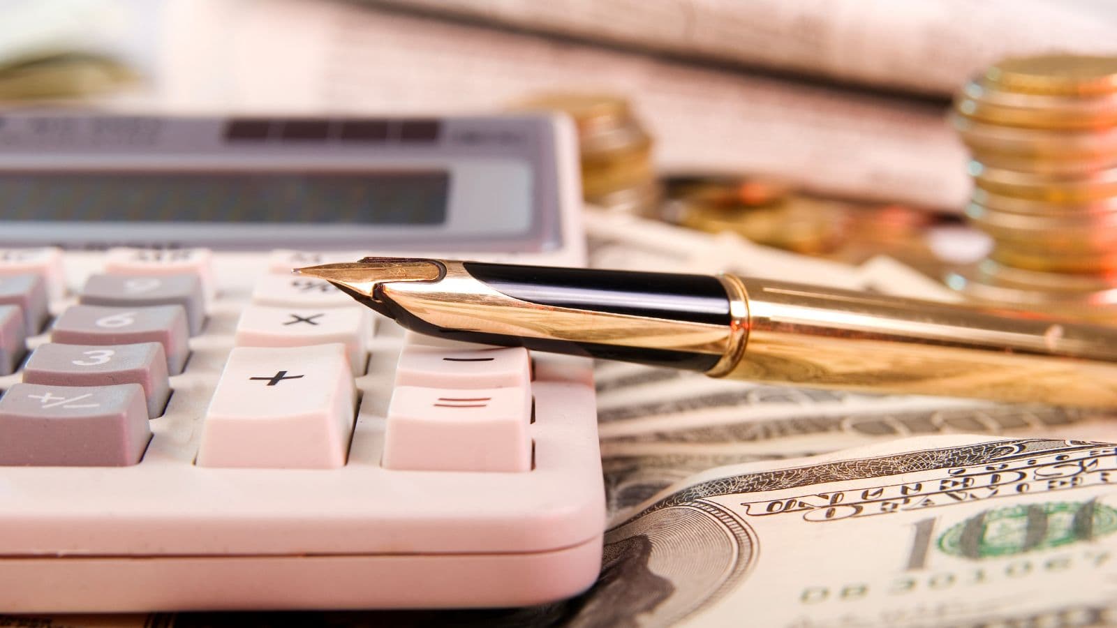 Stylo, calculatrice, pièces et billets sur un bureau