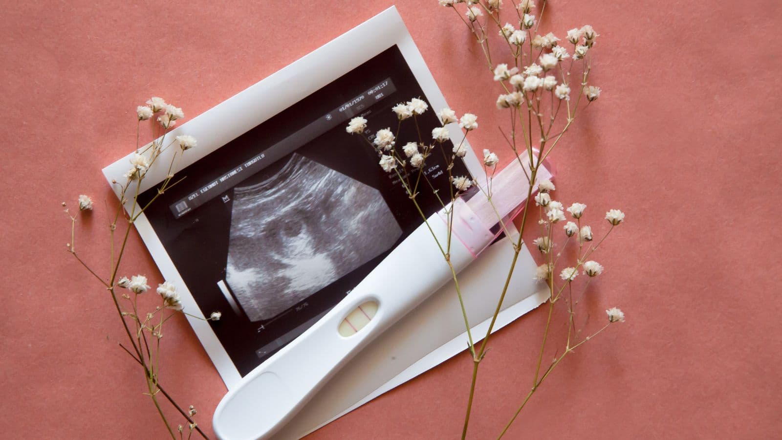 Test de grossesse positif accompagné d'une échographie et de fleurs